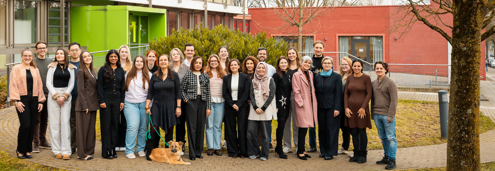 Die Mitglieder des Instituts für Diversitätsstudien (Dezember 2025) laufen über eine Wiese auf dem Campus der TU Dortmund